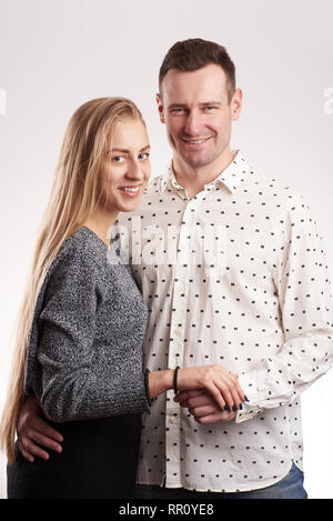 Smiling young caucasian couple standing in studio light isolated Stock Photo