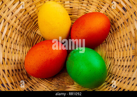 Four colorful easter eggs in basket isolated Stock Photo