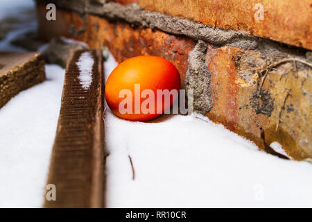 Red easter egg hidden next to a house Stock Photo