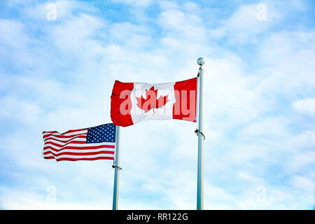 Canadian and American Flag Flying together Stock Photo