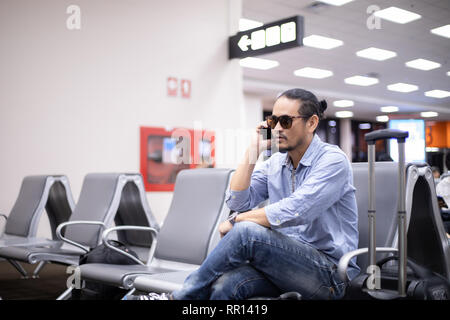 Asian man with backpack  traveler using the smart mobile phone for Video call and taking at an airport Stock Photo