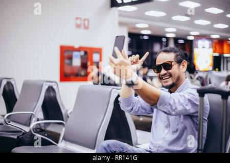 Asian man with backpack  traveler using the smart mobile phone for Video call and taking at an airport Stock Photo