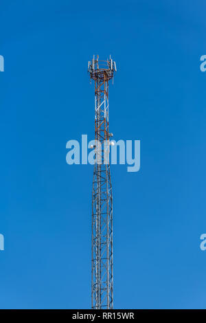 View of a tower with telecommunications antennas, details of the metallic structure and equipment, blue sky as background Stock Photo