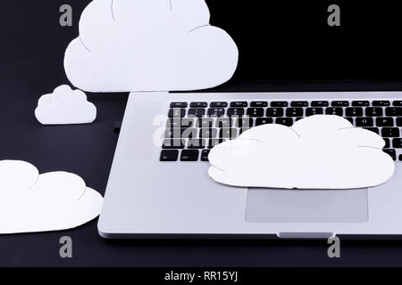 Cloud computing concept with cutout clouds above a laptop computer keyboard on a black background Stock Photo