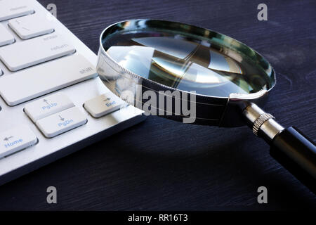 Keyboard and magnifying glass.SEO and IT audit concept. Stock Photo