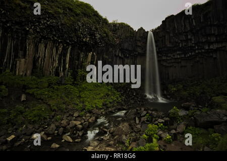 Long exposure of Svartifoss waterfall with its water falling over basalt columns with overcast sky in top. Skaftafell National Park in Southern Icelan Stock Photo