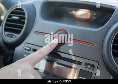 Woman pressing hazard lights button. Inside car view Stock Photo