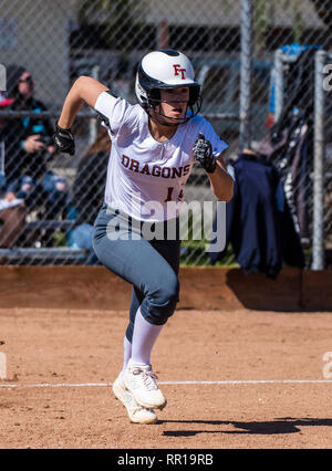 Softball player in white uniform running full speed to first base during game between Foothill Technology High School and Pioneer Valley on February 2 Stock Photo