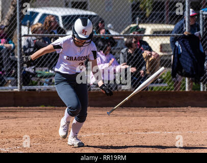 Softball player in white uniform running full speed while flinging bat to the side during game between Foothill Technology High School and Pioneer Val Stock Photo