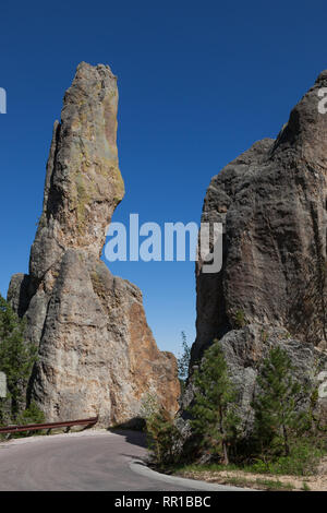 Eroded rock formations and trees stand tall against a clear blue spring sky next to Needles Highway in Custer State Park, South Dakota. Stock Photo