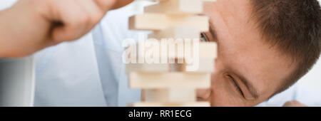 Businessman plays in a strategy of jenga hand Stock Photo