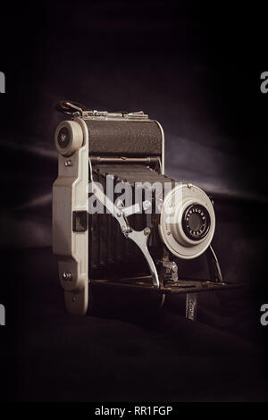 Vertical aspect right side view of an unbranded vintage roll film camera against a black background. Stock Photo