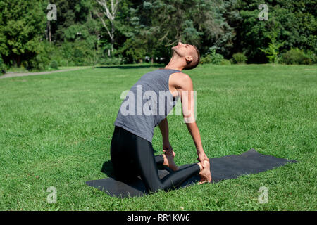 Healthy Lifestyle. Man practicing yoga on mat outdoors in camel pose bending back Stock Photo