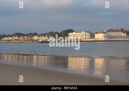 View from Shell Bay on the Studland Peninsula across Poole Harbour to Sandbanks in the late afternoon with reflections in the sea water, Dorset, UK Stock Photo