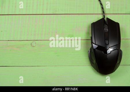 black computer mouse on a green wooden background with copy space for your text. Top view Stock Photo