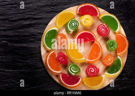 Fruit jellies. Jelly candies citrus in form lobules on a dark background. Top view Stock Photo