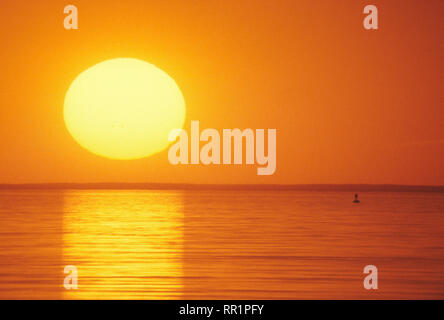 The setting sun as seen through a long telephoto lens over Cape Cod Bay ...