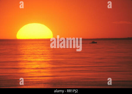The setting sun as seen through a long telephoto lens over Cape Cod Bay ...
