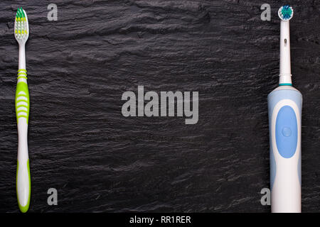 electric and manual toothbrushes on black stone background with copy space for your text. Top view Stock Photo