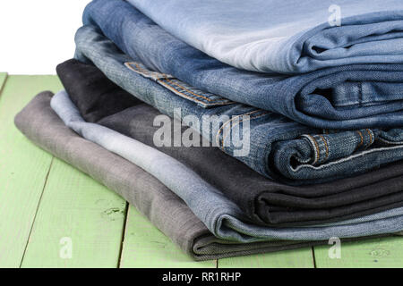 stack of jeans on green wooden background Stock Photo
