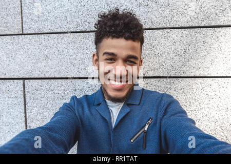 Freestyle. Mulatto guy standing isolated on wall taking selfie looking camera cheerful close-up Stock Photo