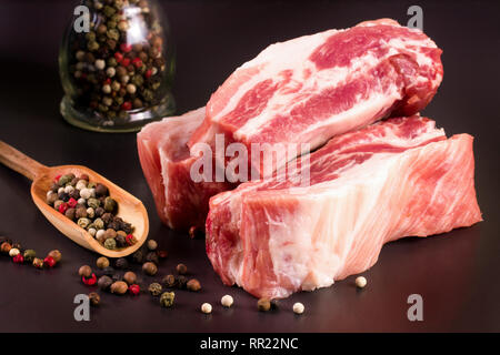 piece of pork on a dark background with peppercorn Stock Photo