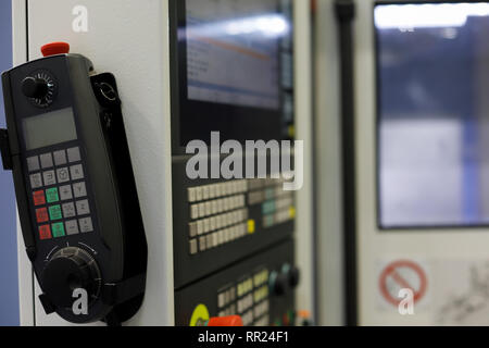 Pendant manual remote control of 4 axis CNC lathe with handwheel and LCD screen. Selective focus. Stock Photo