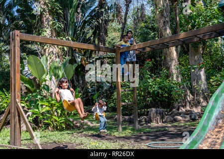 latin siblings playing on playground in Guatemala Stock Photo