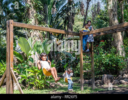 latin siblings playing on playground in Guatemala Stock Photo