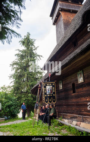 Villagers and banners used for a Pentecost procession outside the wooden church in Poienile Izei in the Maramure? region in Romania. Stock Photo