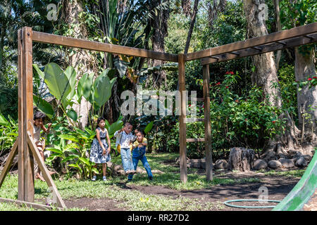 latin siblings playing on playground in Guatemala Stock Photo