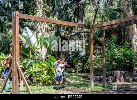 latin siblings playing on playground in Guatemala Stock Photo