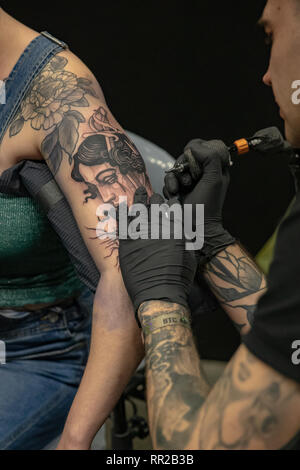 Brighton, UK. 23rd Feb, 2019. Tattoo artist works on a client at the the 12th annual Brighton Tattoo Convention at the Brighton Centre, England. Credit: Jason Richardson/Alamy Live News Stock Photo