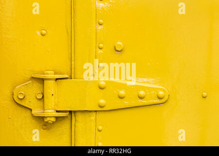 door hinge closeup view on yellow painted abstract grunge background Stock Photo