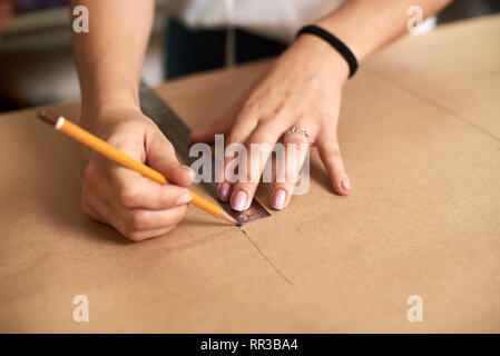 Work place in design studio. Professional female designer hands close-up making paper patterns using measuring tape, ruler and curves. Exclusive clothes making, creative occupation concept. Stock Photo
