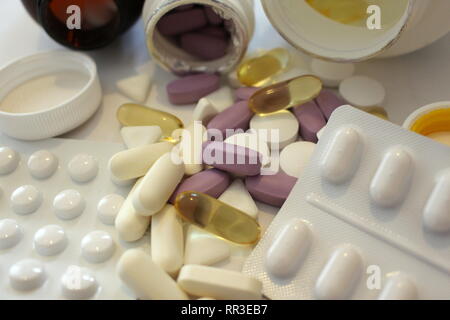 A close up photograph of a variety of medication, tablets and pills spilling from their bottles onto a white surface. Healthcare, illness concept Stock Photo