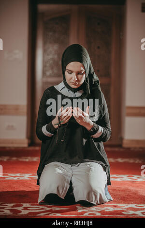 Muslim girl with hijab praying and reading quran in mosque Stock Photo