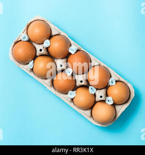 Brown Easter eggs in an eco carton pack lie on a beautiful blue background. Easter ideas. Space for text. Happy easter. Stock Photo