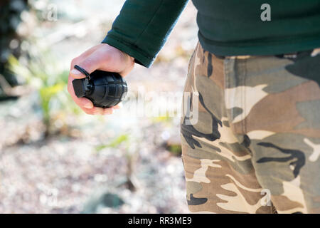 Close up on the hand of a man holding a grenade outdoors in a concept of terrorism or combat Stock Photo