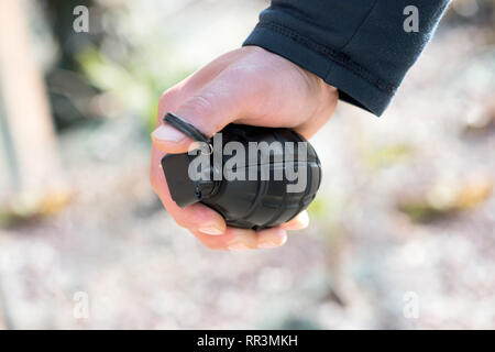 Man clutching a grenade in his hand with his thumb through the ring of the pin in a concept of terrorism or war Stock Photo