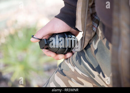 Close up cropped view of a man in camouflage clothing holding a grenade in his hand Stock Photo