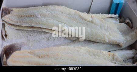 Salted dried codfish in a carton box, background, texture. Closeup view Stock Photo