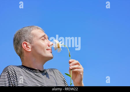 The man enjoys aroma of a spring flower Stock Photo