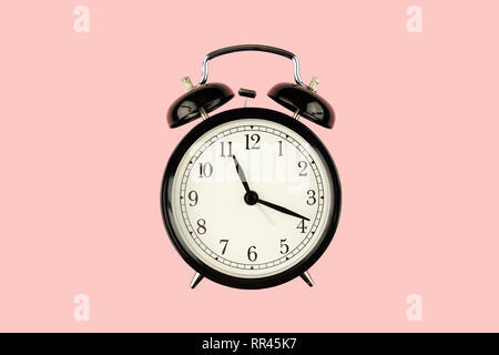 Black retro alarm clock on pink background closeup Stock Photo