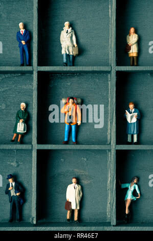 miniature figurines in a box with compartments, concept for pigeonholing and social distancing Stock Photo
