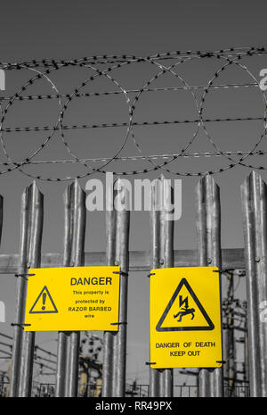 Warning signs and razor wire surround a electricity substation in Ducklington Oxfordshire UK Stock Photo