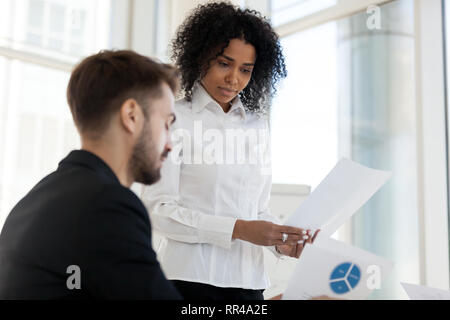 Team leader and colleague looking at statistics shown on document Stock Photo