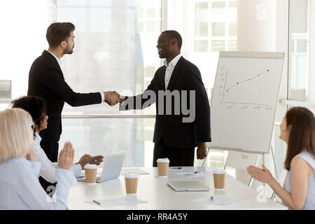 Diverse businessmen standing in office and shaking hands Stock Photo