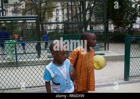 French children of African origin, brothers, boy wearing traditional dashiki shirt, holding sponge ball, Square de Maubeuge, 75009, Paris, France Stock Photo