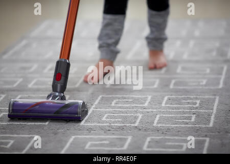 Boy using a vacuum cleaner while cleaning carpet in the house Stock Photo